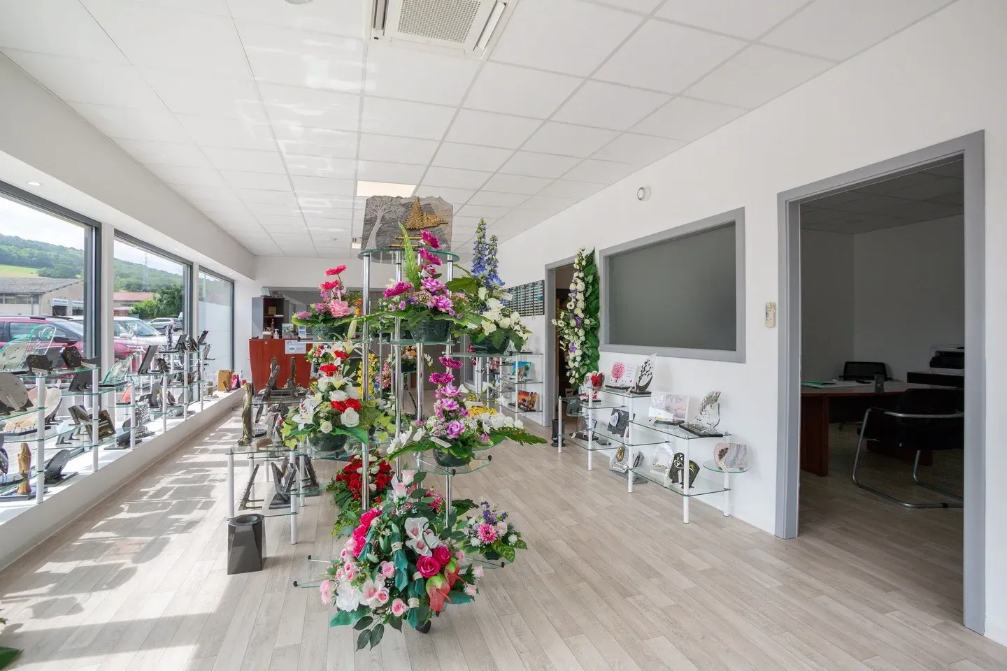 Magasin de pompes funèbres avec fleurs artificielles et plaques commémoratives.
